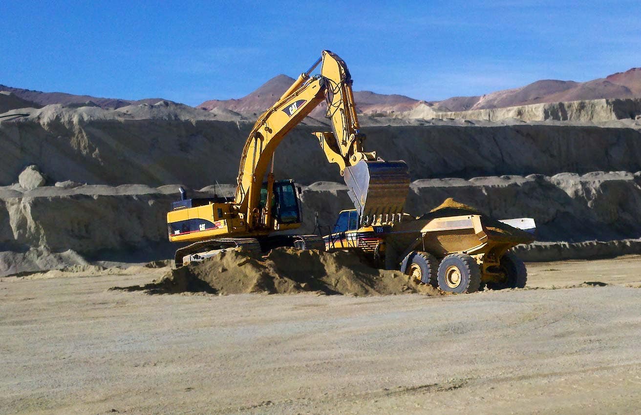 Photo of a backhoe filling a dump truck.